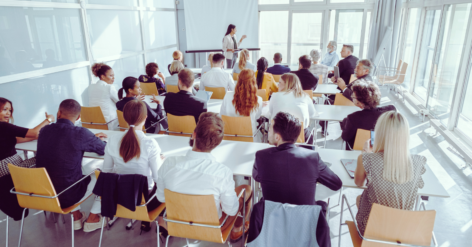 Grupa osób uczestniczących w seminarium biznesowym w jasnej, nowoczesnej sali konferencyjnej.